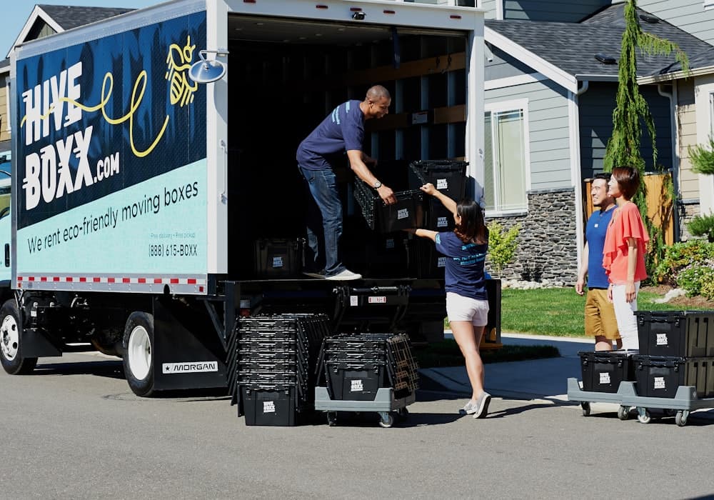 Man and van crew handing a moving crate to a customer outside their home