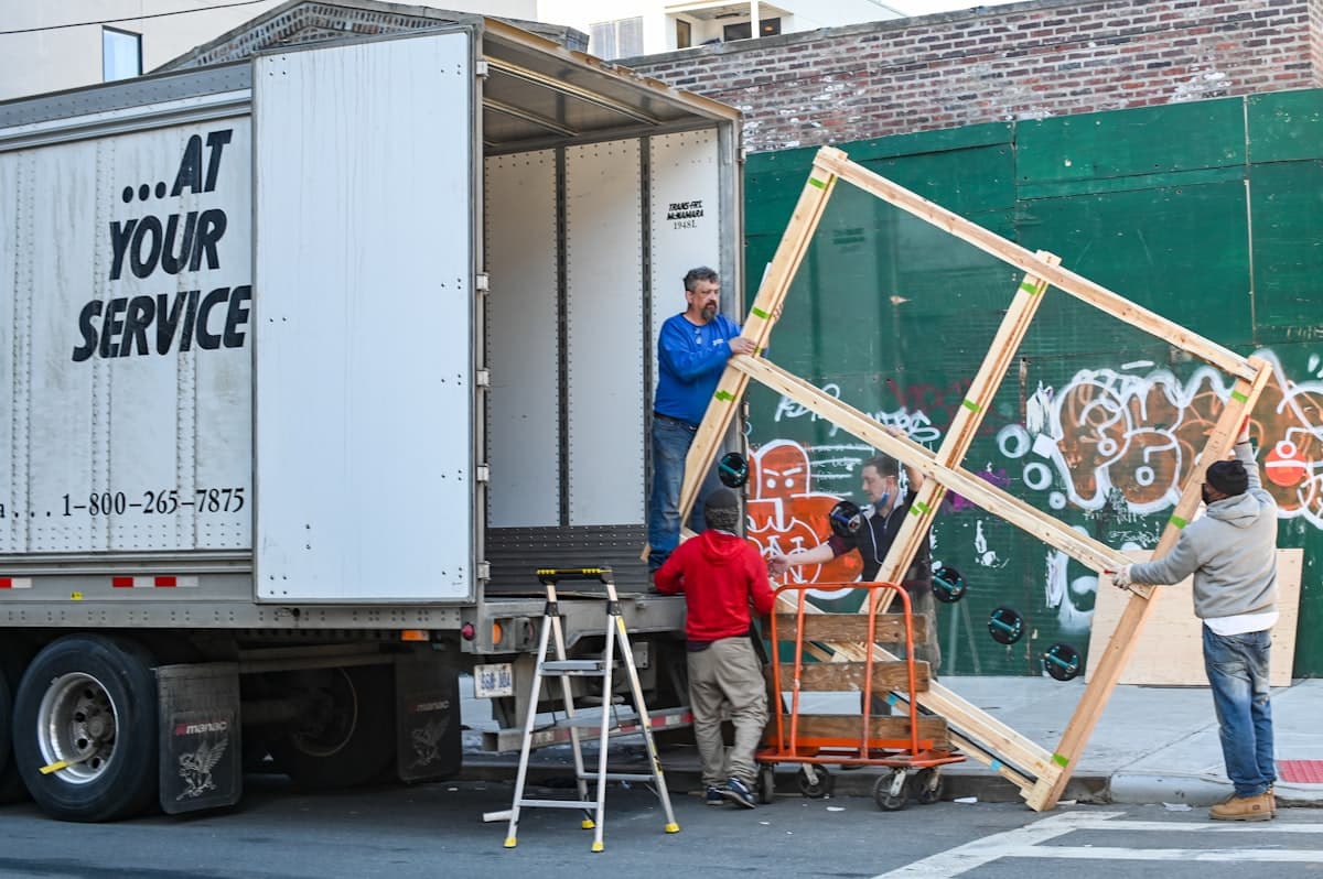 Removal crew carefully carrying a large piece of furniture from a van